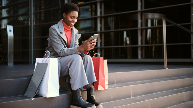 Person sitting down after shopping and looking at phone
