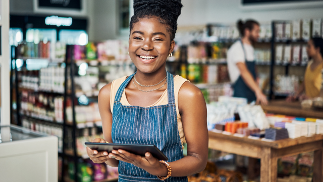 Grocery store employee holding tablet and smiling