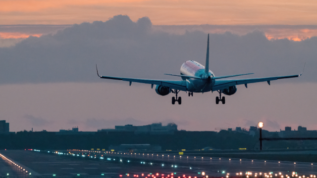 Airplane landing at an airport during sunset.