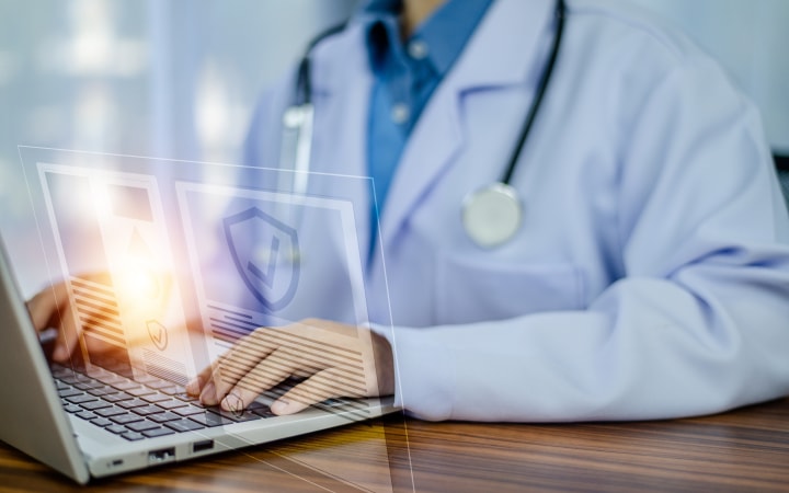 A medical professional typing on a laptop