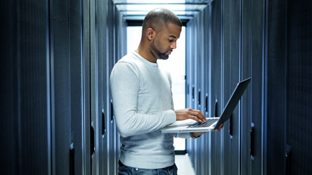 Person looking at a laptop in a server room