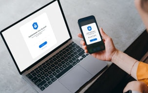 Person working on a laptop and looking at a mobile device