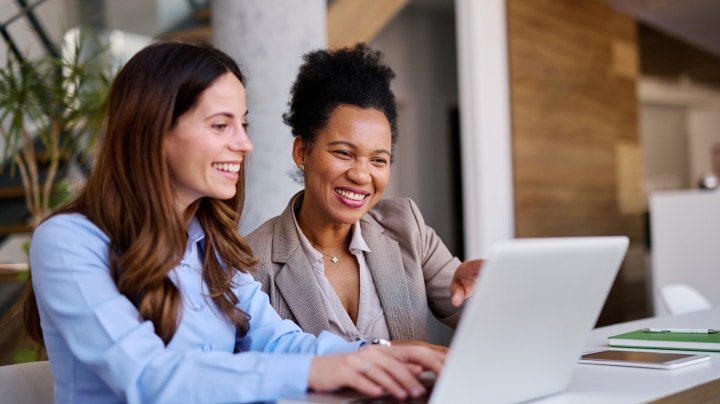 Two professionals reviewing documents on a laptop