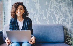 Woman laughing with computer on lap