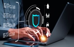Person typing on a laptop with a digital security shield icon.