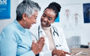 Patient and healthcare provider reviewing information on a tablet in a clinic.