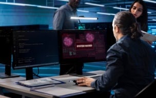 Person working at multiple computer monitors in a cybersecurity operations center.