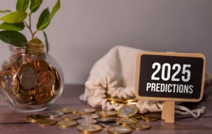 2025 Predictions written on a small chalkboard placed on a table with some currency coins and a plant