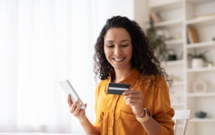 A person holding a phone and a banking debit/credit card