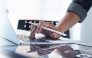 A person using stylus on their laptop with a digital banking icon