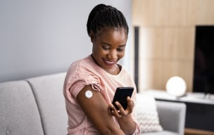 A person using a healthcare device on their arm and using their smartphone