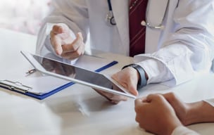 A doctor explaining to another person while pointing towards their ipad