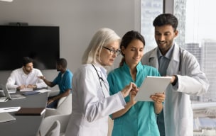 Three doctors discussing something while looking into an ipad