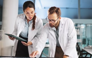 Two doctors working on a machine and one of them is holding an ipad