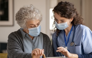 Doctor and patient wearing masks and looking at a tablet