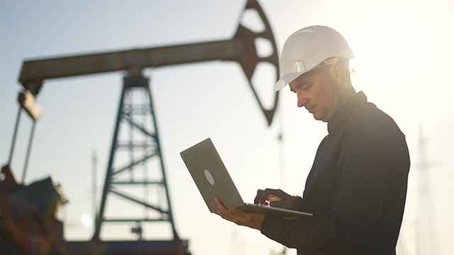 Man in hardhat near oil pumpjack 