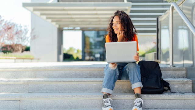 A person with laptop sitting on stairs