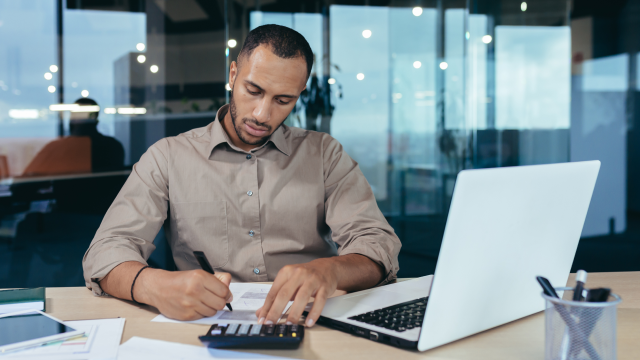 An office employee writing on a financial worksheet