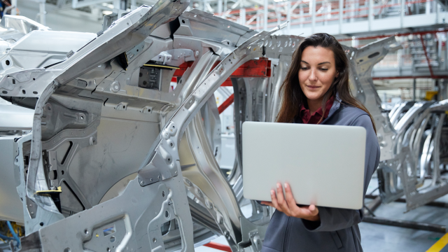 A person looking at a laptop in an automotive facility