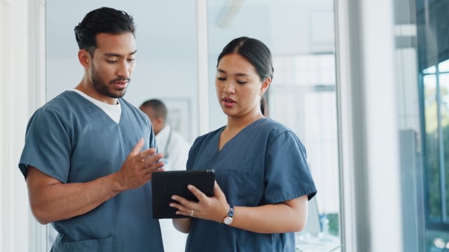 Two doctors are having a discussion while using a tablet