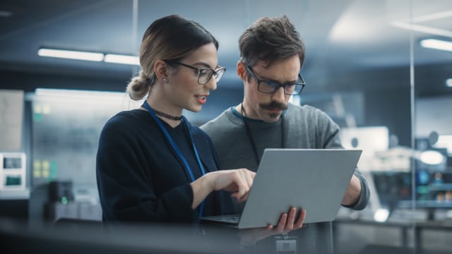 Two people working on their laptop in an office