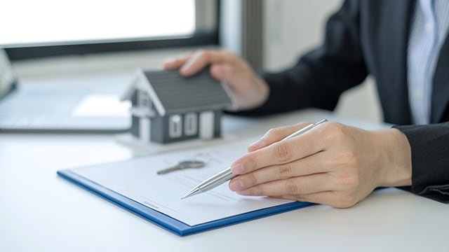 Person holding pen over paperwork