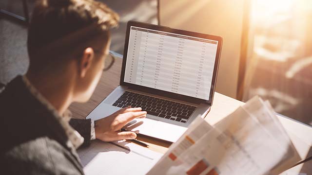 Man working on laptop with paperwork