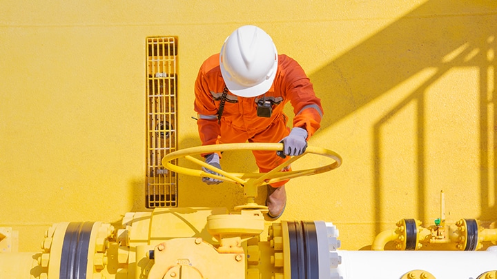 Man and woman in safety gear and hard hat looking at screens