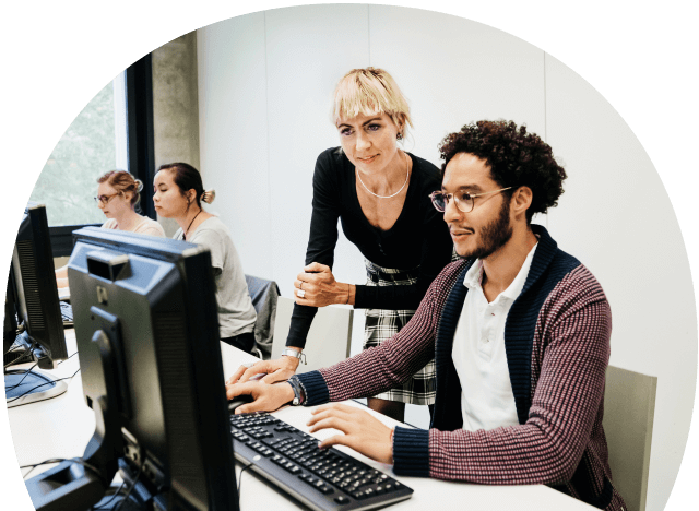 two people working on a computer in a classroom