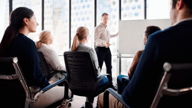 people in an office meeting with a whiteboard