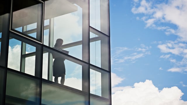 A person in working on a tablet by the window of an office building