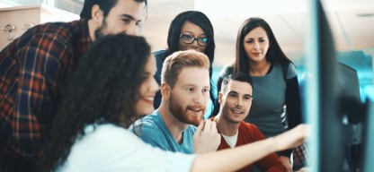A group of people working around a computer