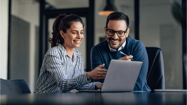 Two people looking at a laptop smiling