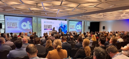 A group of professionals at a conference listening to the speaker on stage